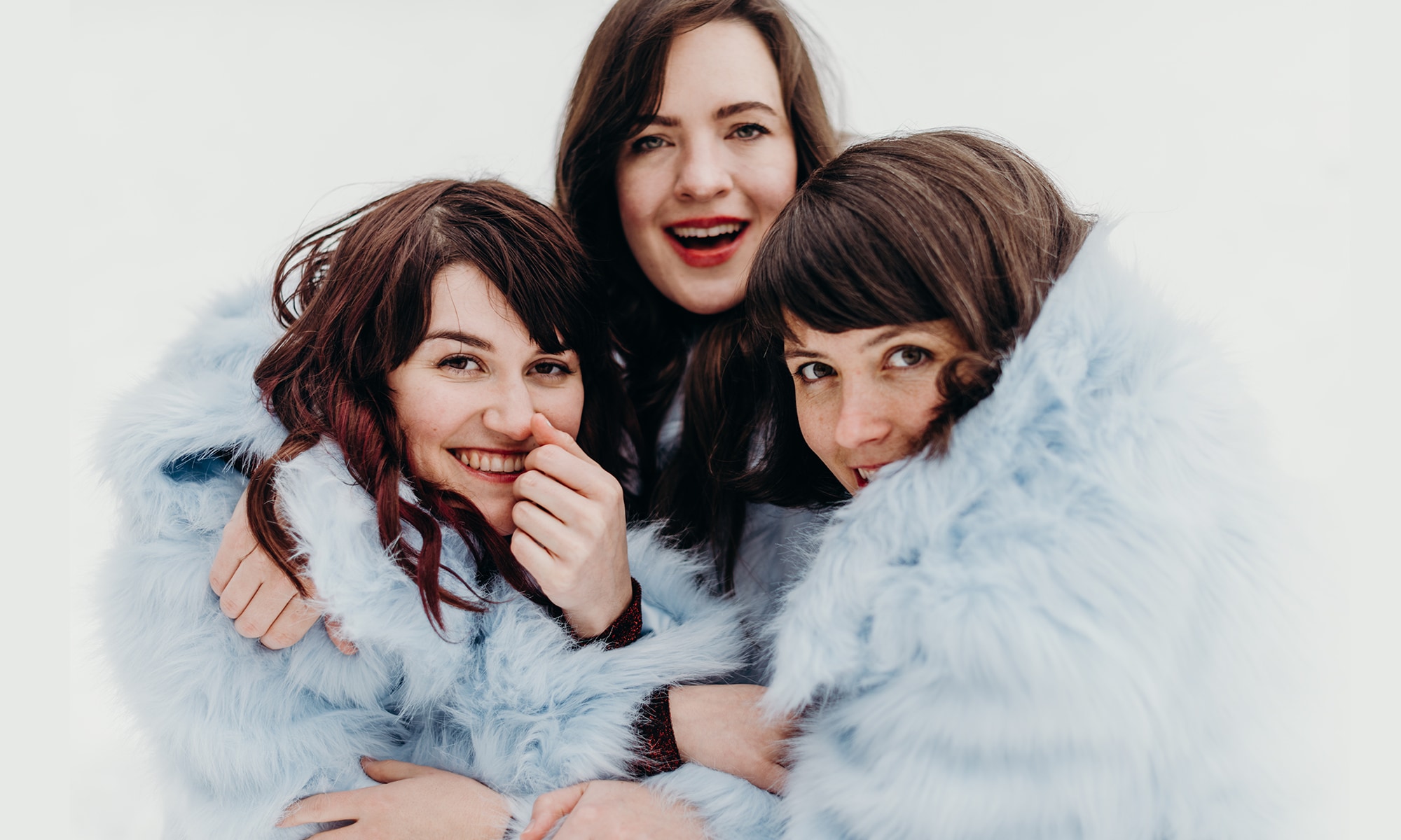 Three female singers in blue furry jackets