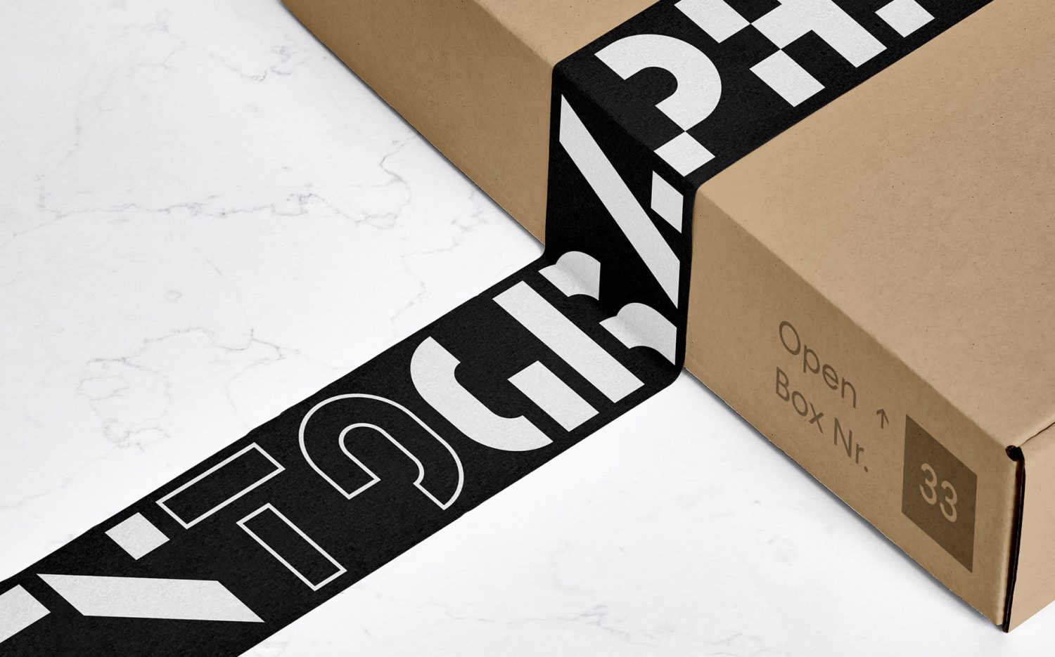 A shipping box sitting on a marble table with black and white graphic packing tape designed by Mary Rauzi