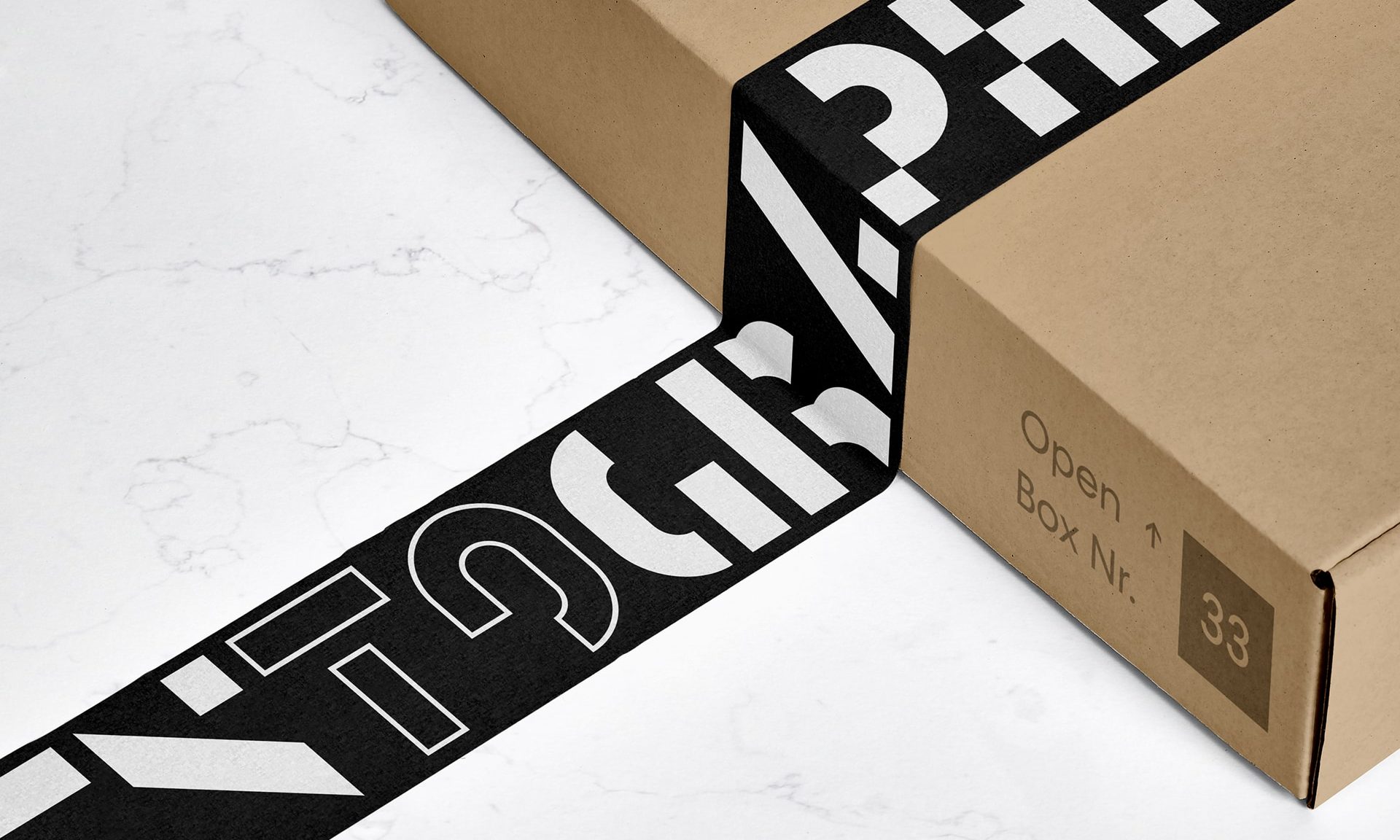 A shipping box sitting on a marble table with black and white graphic packing tape designed by Mary Rauzi
